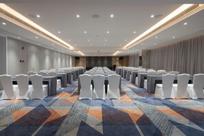 A conference room with rows of tables and chairs, a patterned carpet, and a modern ceiling design. - Ji Hotel Guangzhou Tianhe Sports Center (Guangzhou)