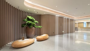 A spacious lobby with a modern design, featuring a large potted plant, wooden seating, and a sleek reception desk. - Ji Hotel Guangzhou Tianhe Sports Center (Guangzhou)