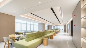 A modern hotel lobby with a green seating area, wooden tables, and a spacious layout. - Ji Hotel Guangzhou Tianhe Sports Center (Guangzhou)
