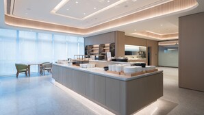 A modern hotel lobby with a central island, seating area, and large windows. - Ji Hotel Guangzhou Tianhe Sports Center (Guangzhou)