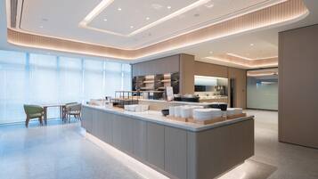A modern hotel lobby with a central island, seating area, and large windows.