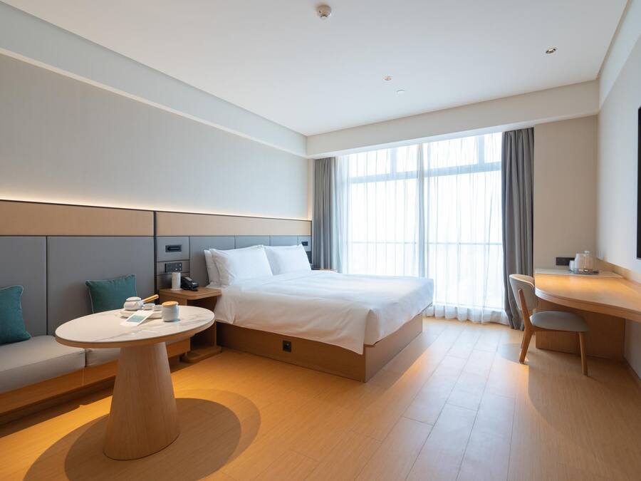 Habitació d'hotel moderna amb un llit, una taula rodona, un sofà i un escriptori.