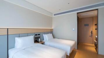 Habitación de hotel con dos camas, una mesita de noche con teléfono y una puerta que da a un baño.