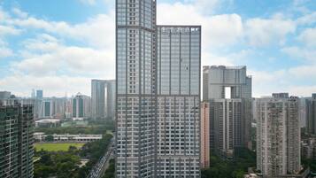 A high-rise hotel with a distinctive angular design, surrounded by other tall buildings and a green park area.