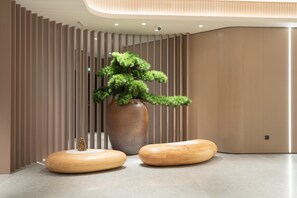 A modern interior with a large potted plant, wooden seating, and vertical wooden slats. - Ji Hotel Guangzhou Tianhe Sports Center (Guangzhou)