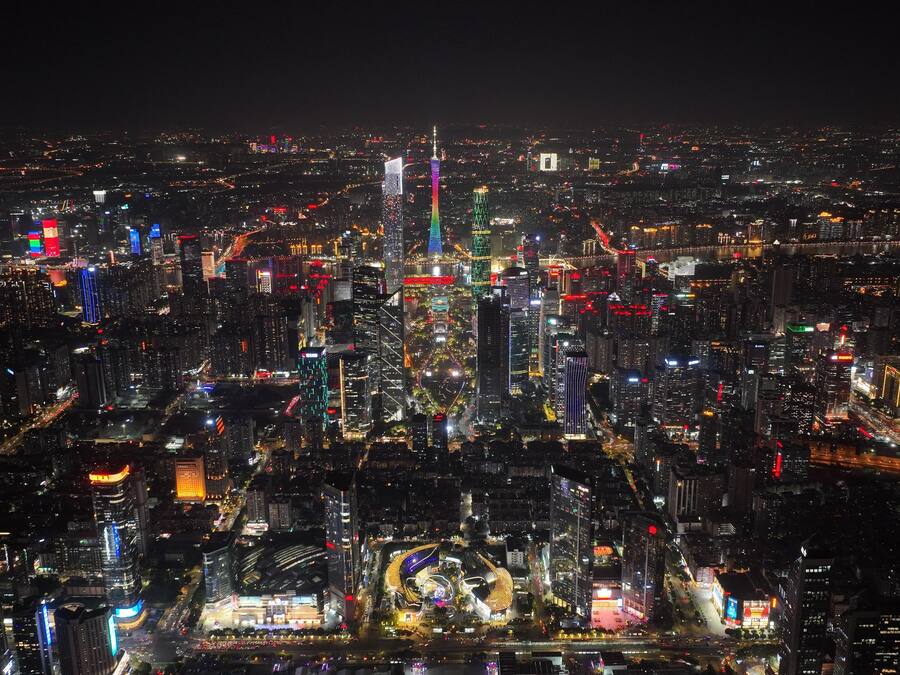A nighttime cityscape with illuminated skyscrapers and a prominent tower.