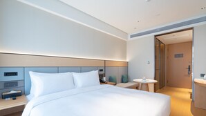 A modern hotel room with a large bed, bedside tables, a small round table, and a separate bathroom area. - Ji Hotel Guangzhou Tianhe Sports Center (Guangzhou)