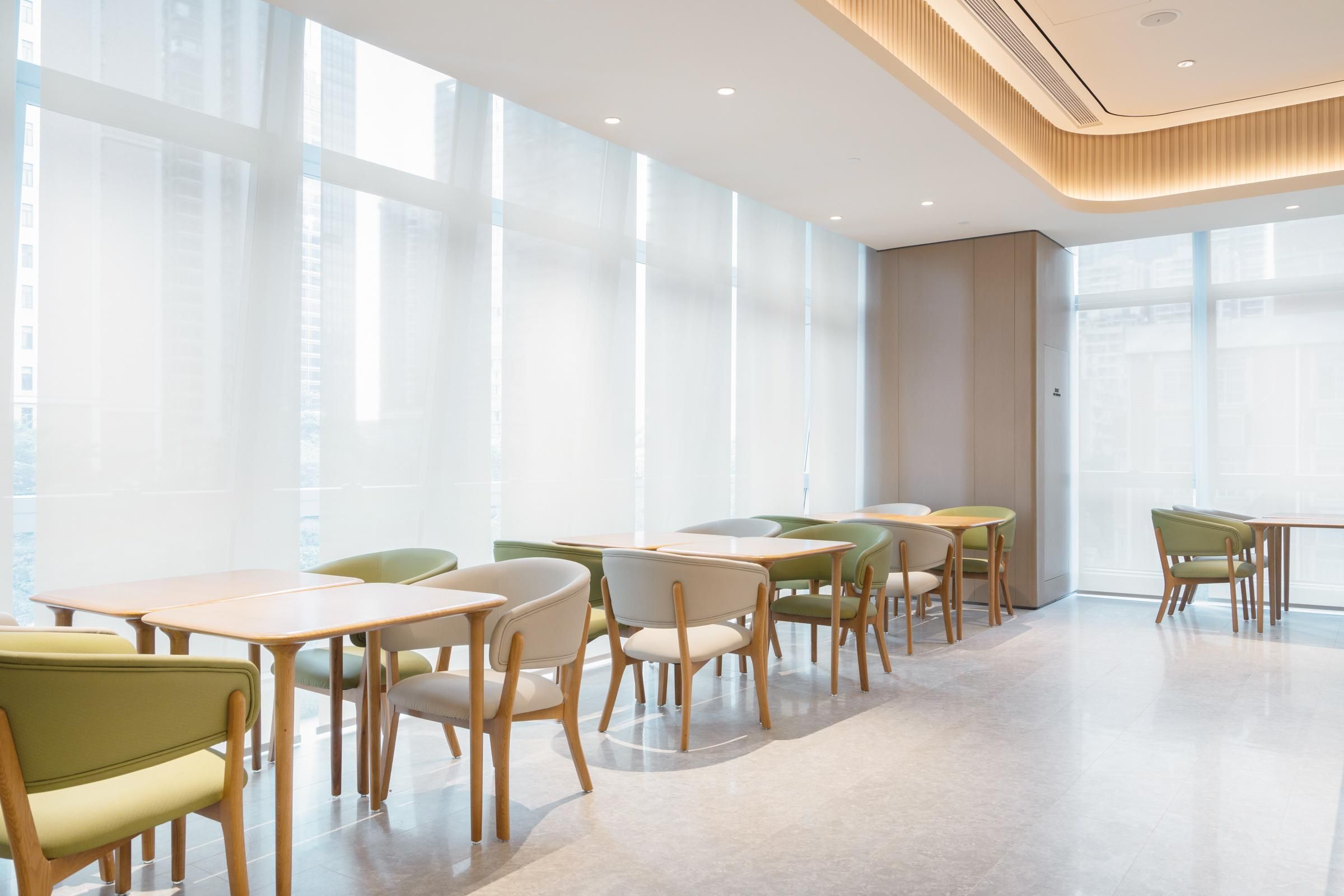 A modern dining area with tables and chairs, large windows, and a clean, minimalist design.