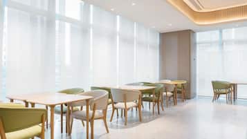 A modern dining area with tables and chairs, large windows, and a clean, minimalist design.