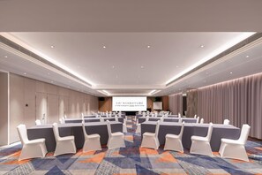 A conference room with rows of chairs, a projection screen, and a patterned carpet. - Ji Hotel Guangzhou Tianhe Sports Center (Guangzhou)