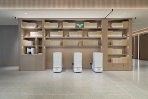 A modern interior with a central bookshelf, a coffee machine, and three white vending machines.