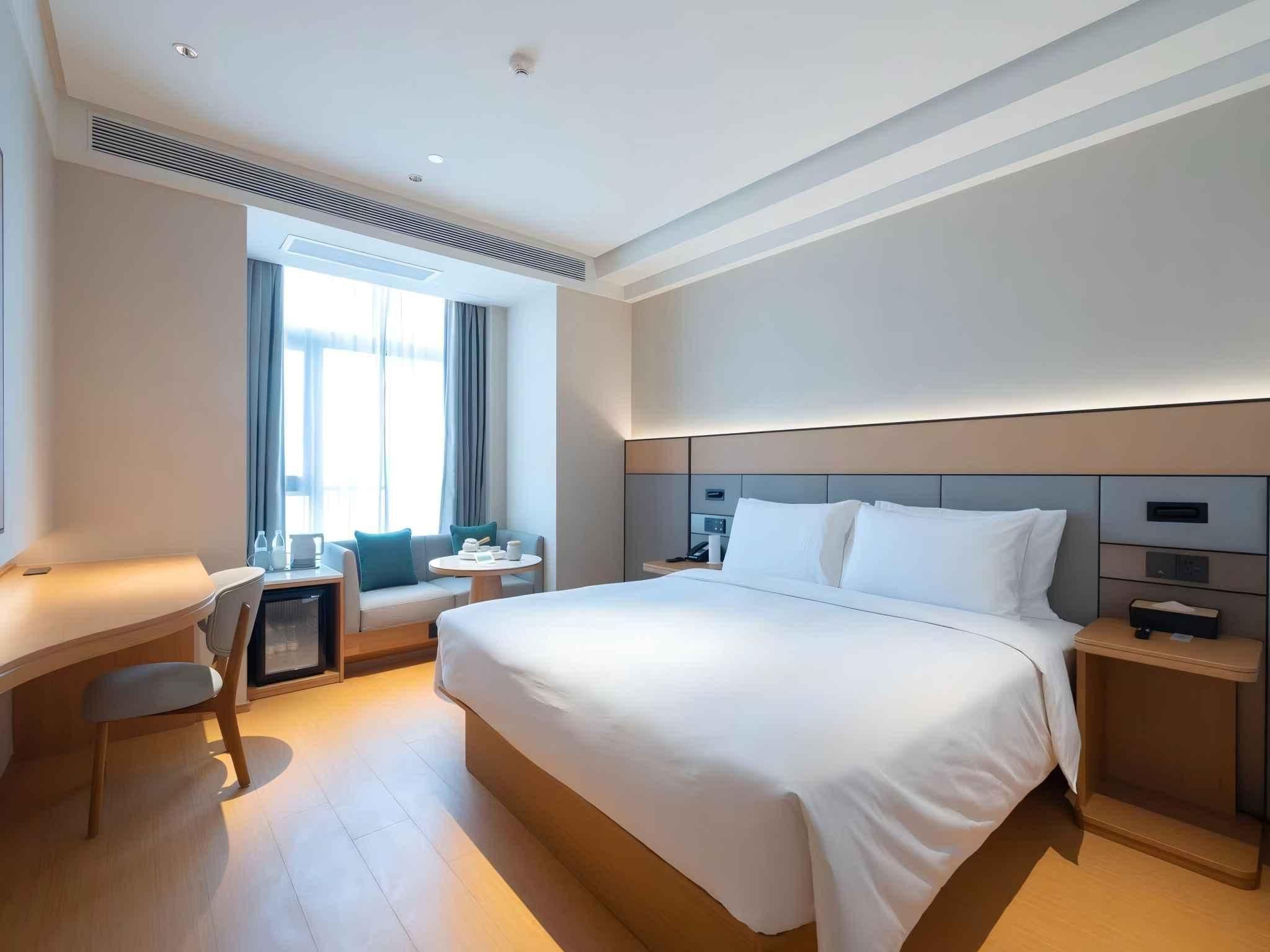 A modern hotel room with a large bed, a desk, and a chair.