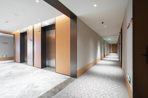 A modern hallway with elevators, a patterned carpet, and a clean, minimalist design. - Ji Hotel Guangzhou Tianhe Sports Center (Guangzhou)