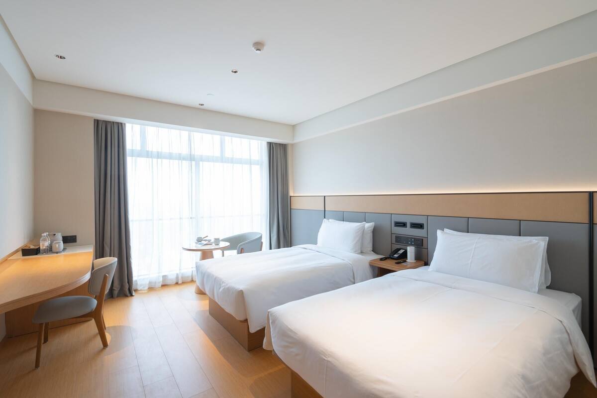 Una habitación de hotel con dos camas, un escritorio, una silla y una mesita.