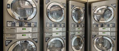 A row of stacked laundry machines in a commercial setting.