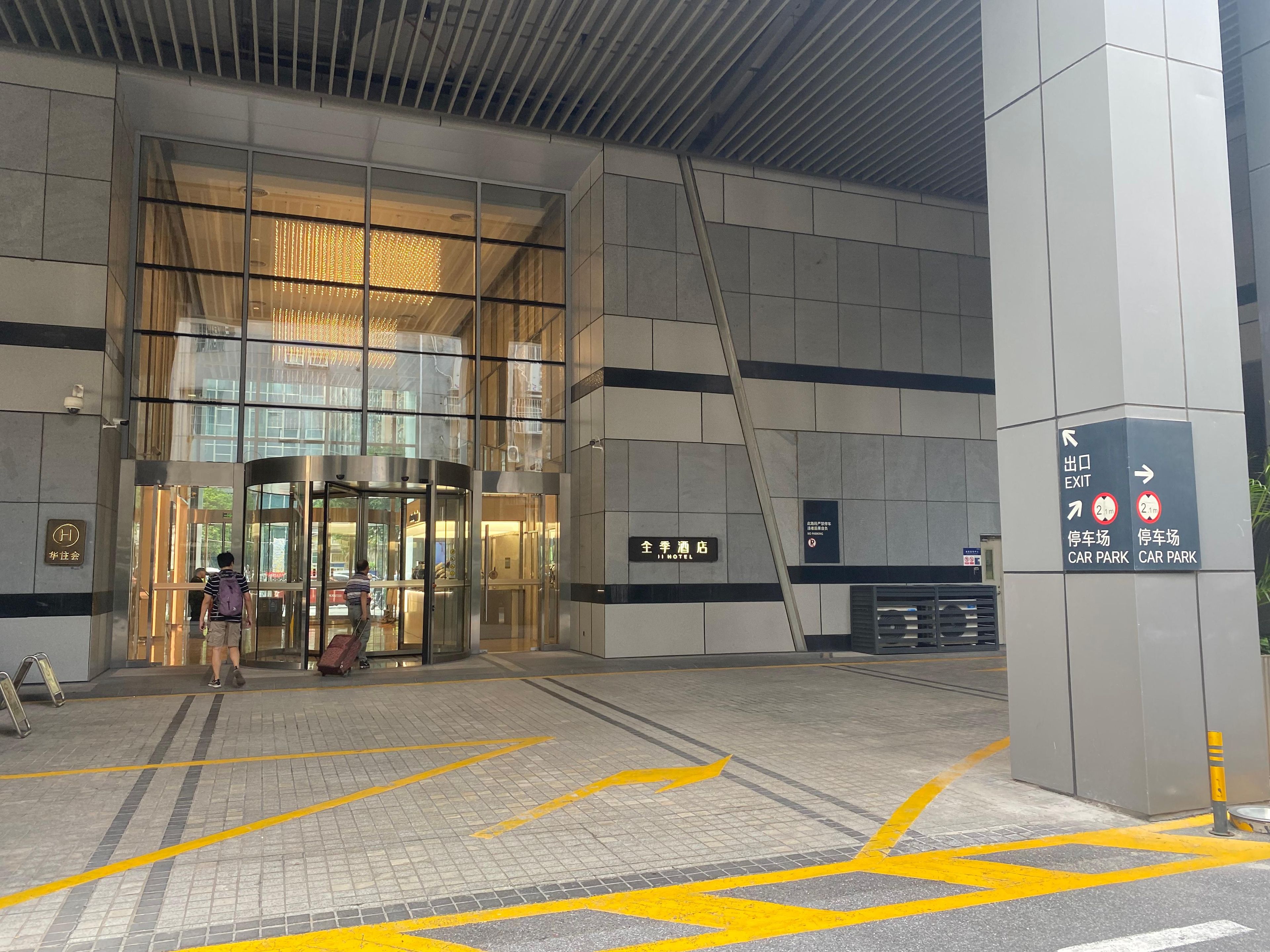 A hotel entrance with a revolving door, clear signage for exits and car parks, and a tiled floor with directional arrows.
