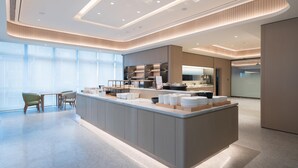 A modern hotel lobby with a central island, seating area, and large windows. - Ji Hotel Guangzhou Tianhe Sports Center (Guangzhou)