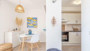 A modern kitchen with white cabinets, a dining area with a white table and chairs, and a hanging light fixture. - Casa Do by Interhome (Roses)