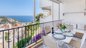 A balcony with a table set for dining, overlooking a coastal town and the sea. - Casa Do by Interhome (Roses)