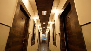 A long, narrow hallway with wooden doors and a dark ceiling. - Hotel Alishaan (Ajmer)