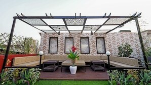 A covered outdoor seating area with a patterned wall and a pergola overhead. - Hotel Alishaan (Ajmer)