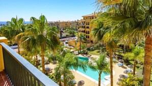 A resort with a pool surrounded by palm trees and sun loungers.