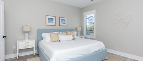 Un dormitorio con cama, mesitas de noche, ventilador de techo y ventana con persianas.
