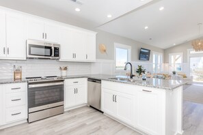 Cocina moderna con armarios blancos, electrodomésticos de acero inoxidable, encimera de granito y una isla grande con asientos.