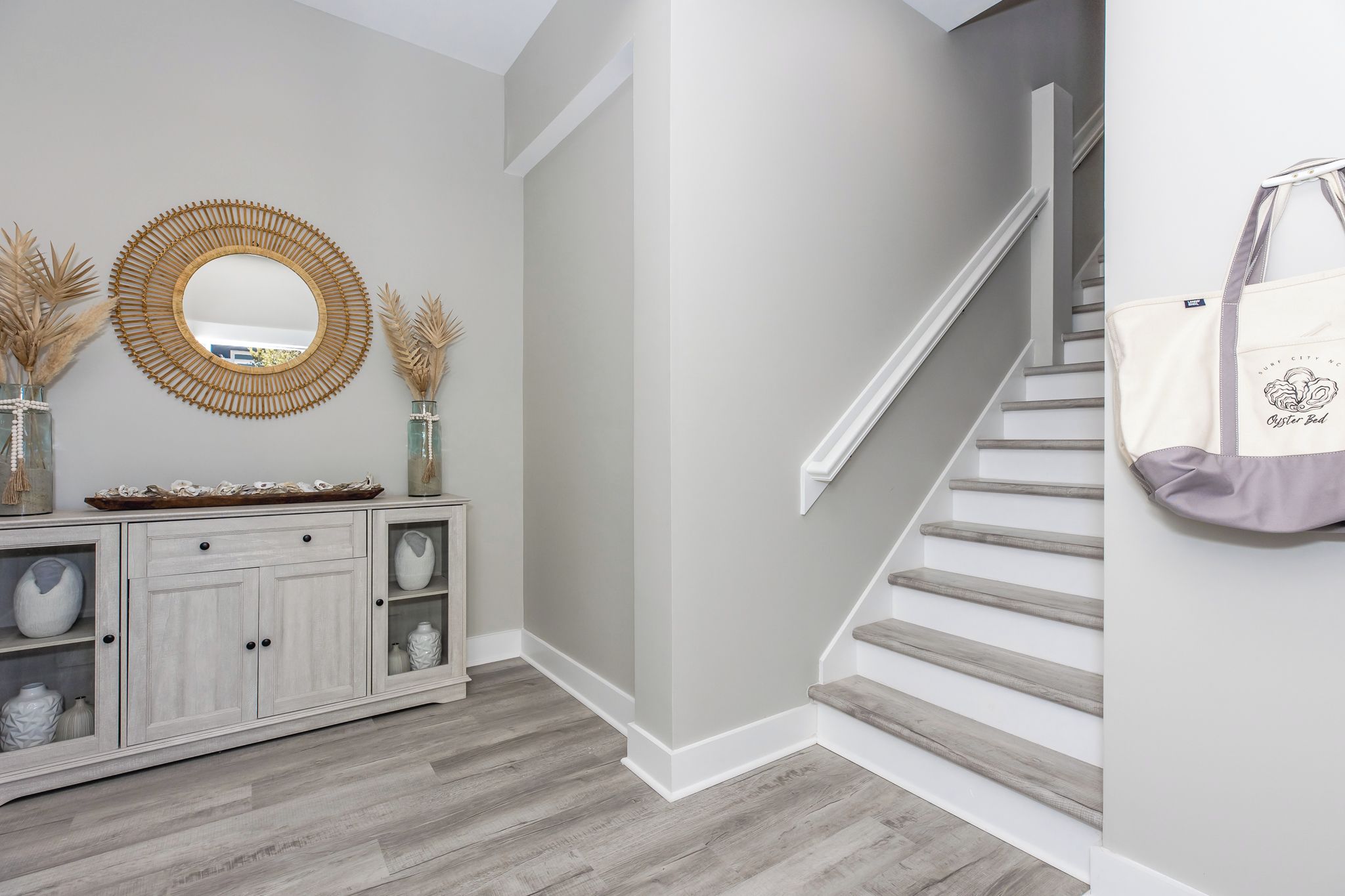 A staircase with a white railing and a bag hanging on the wall.