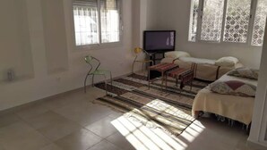 A room with a bed, a television, a chair, and a window with blinds. - Great studio in El-Biar (Algiers)
