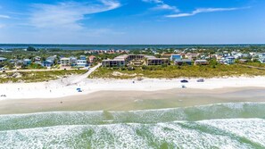A coastal area with beachfront properties, a sandy beach, and ocean waves.