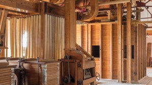 Un interior rústico de madera con vigas a la vista, una gran rueda de madera y varios cofres de madera.