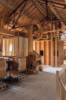 Un interior rústico de madera con vigas a la vista, una gran rueda de madera y varios cofres de madera.