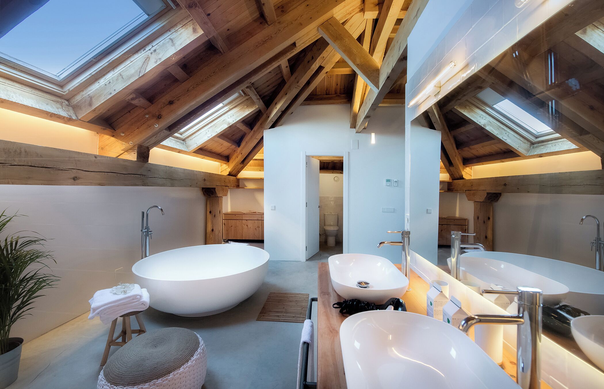 Un baño moderno con tragaluces, una bañera grande y dos lavamanos.