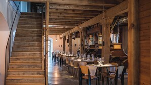 Un restaurante con vigas de madera, una escalera y mesas dispuestas para comer.