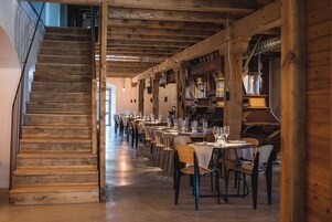 Un restaurante con vigas de madera, una escalera y mesas dispuestas para comer.
