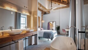 Un baño moderno con una bañera grande, dos lavamanos y una cama con vistas a la ciudad.