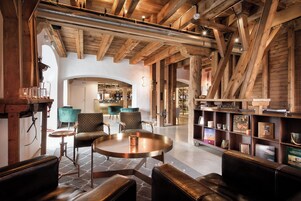 Un vestíbulo espacioso con altos vigas de madera, asientos de cuero y una zona de bar al fondo.