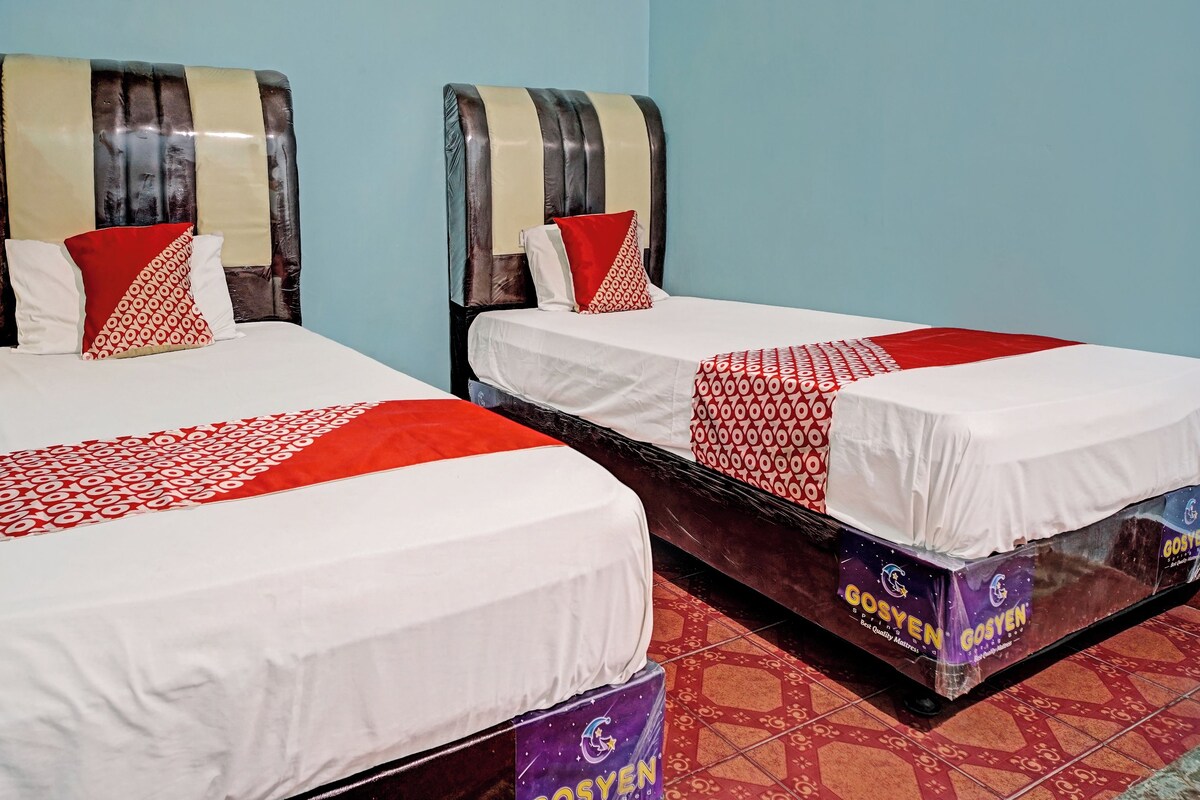 Two twin beds with white and red bedding, wooden headboards, and red pillows.