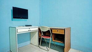 Una habitació petita amb escriptori, cadira i televisió penjada a la paret.