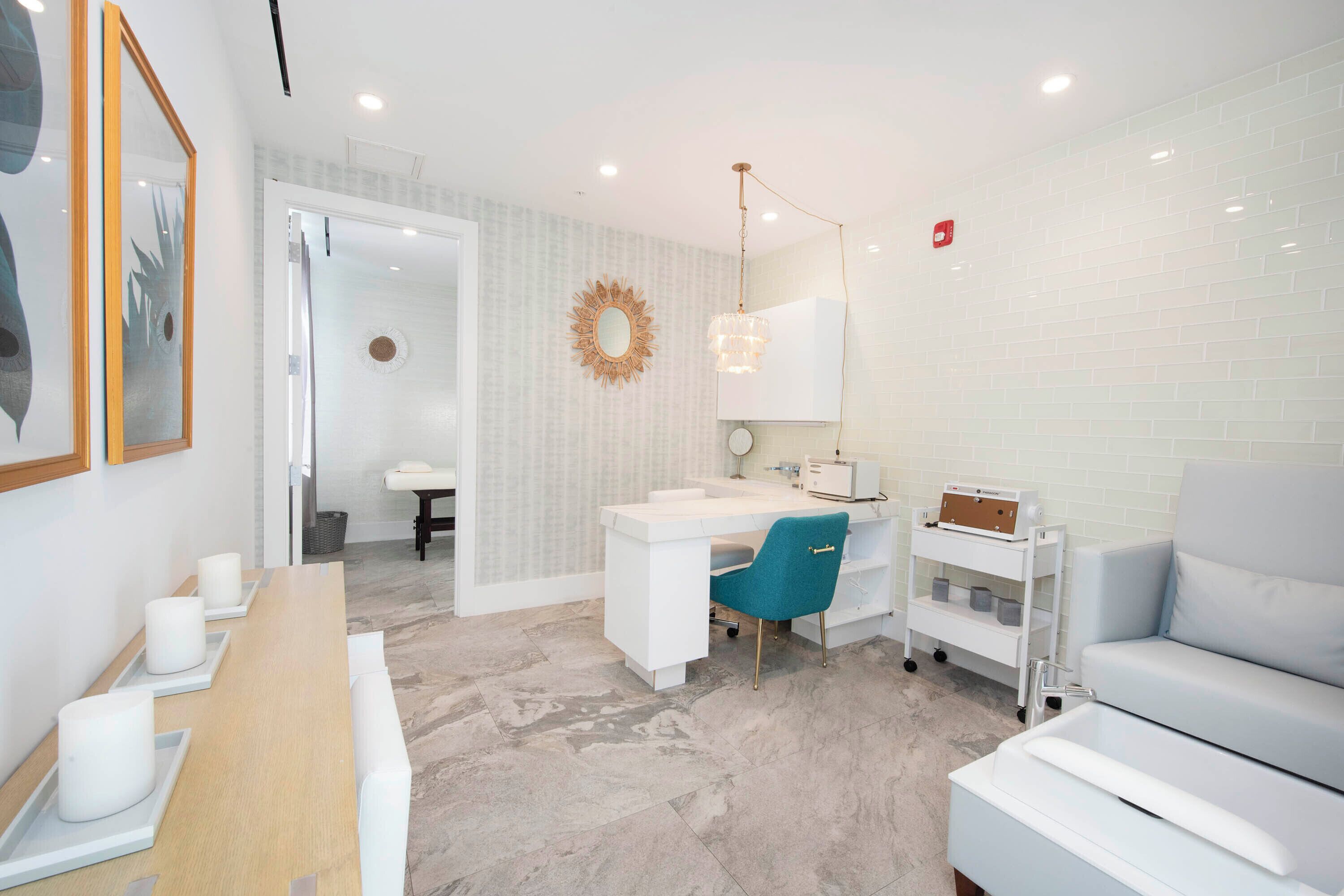 A modern bathroom with a white vanity, a blue chair, a white sofa, and a shower area.