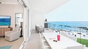 Ein modernes Zimmer mit großem Fenster mit Meerblick, einem weißen Esstisch und einer gemütlichen Sitzecke.