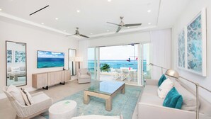 Ein modernes Wohnzimmer mit einem Glastisch, weißen Sofas und Blick auf den Ozean.