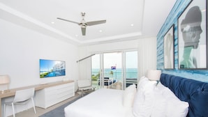 Een moderne hotelkamer met een groot bed, een bureau, een stoel en een balkon met uitzicht op zee.
