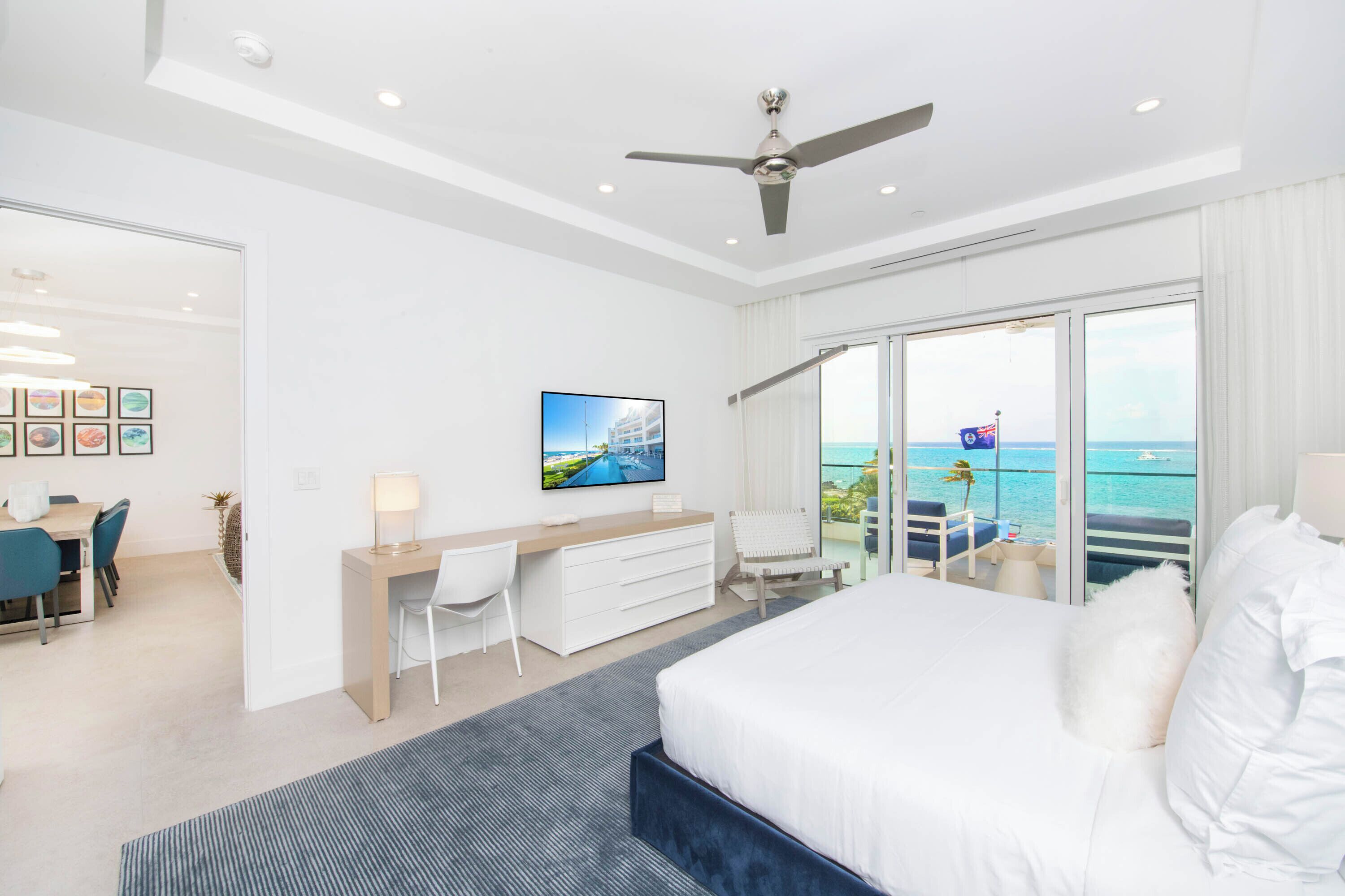 Una habitación de hotel moderna con una cama grande, un escritorio y un balcón con vista al mar.