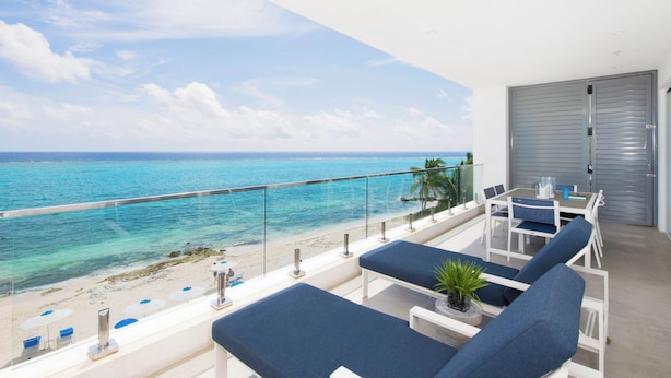 Een balkon met uitzicht op de oceaan, een tafel met stoelen en loungezetels.