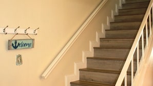 A wooden staircase with white railings, beige walls, and a 'Welcome' sign. - Bayfront canal side condo (Rockport)