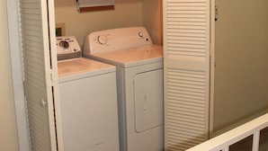 A laundry room with a washing machine, dryer, and a cabinet above the dryer. - Bayfront canal side condo (Rockport)