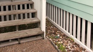 A wooden staircase leading to a door with a wreath, a white railing, and a light fixture above. - Bayfront canal side condo (Rockport)