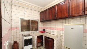 A kitchen with a gas stove, oven, microwave, and refrigerator. - Furnished apartment in Douala, Makepe (Douala)